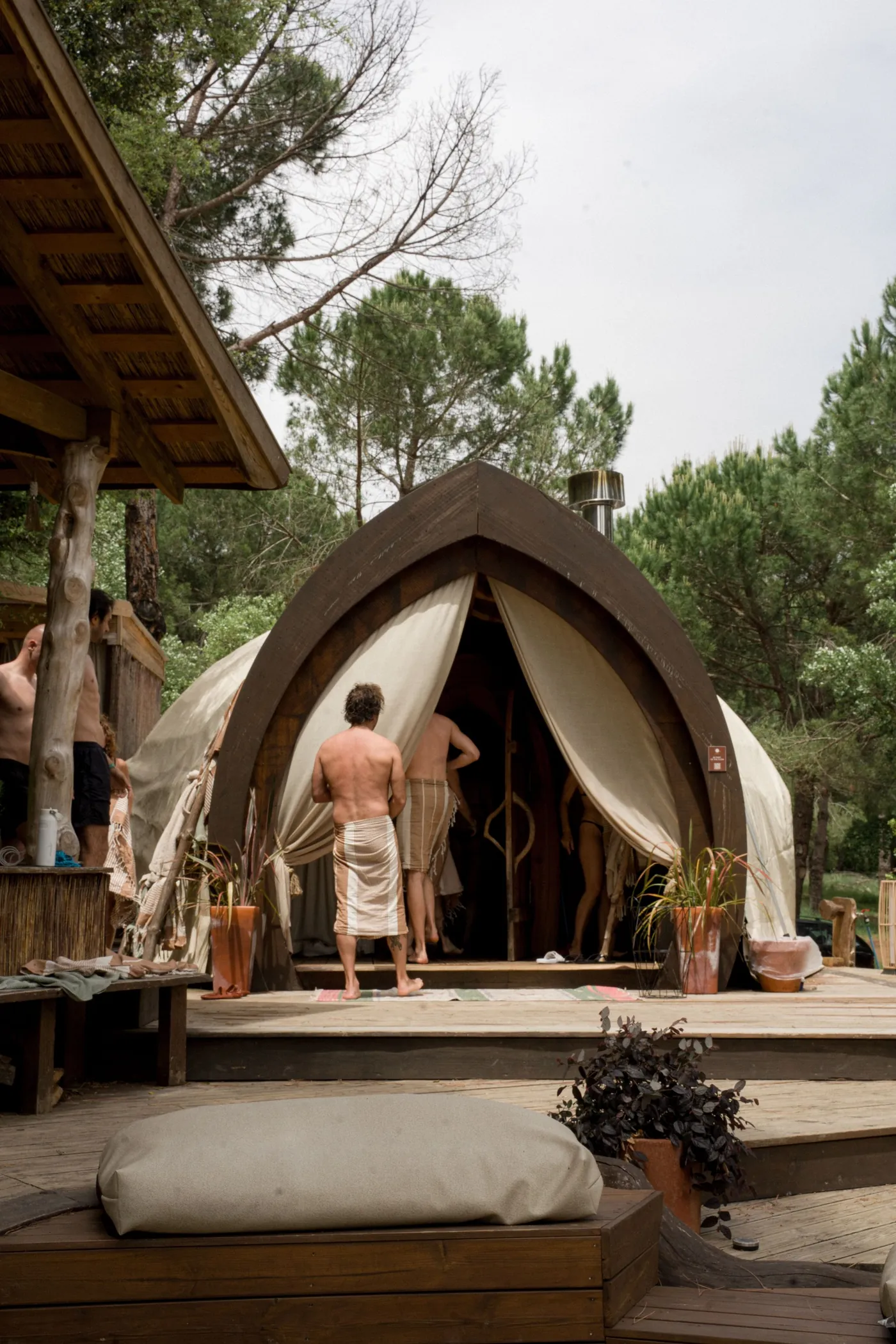 Guests in towels entering the ATMOS steam room among the trees at DOMA